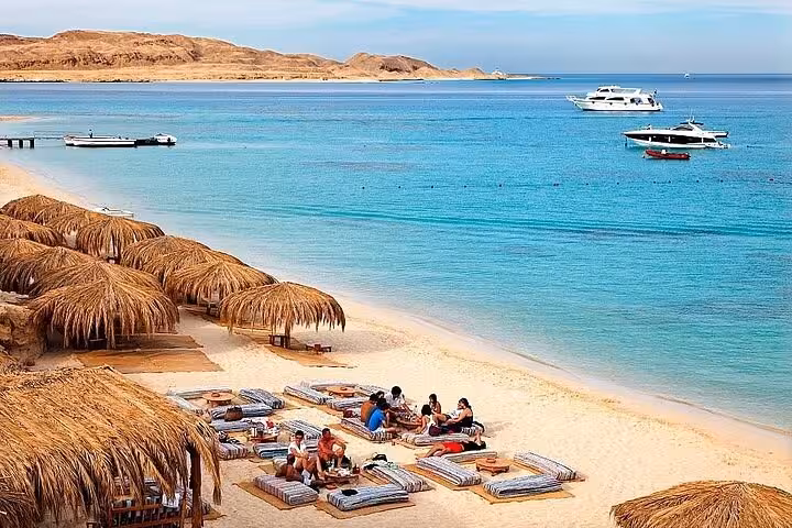 Ain El Sokhna Red Sea beach with straw umbrellas, sunbeds and boats, ideal day tour from Cairo, Egypt