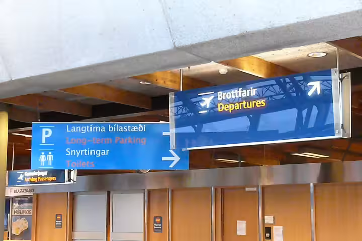 Airport departure signs in Icelandic and English showing directions to departures, long-term parking, and toilets