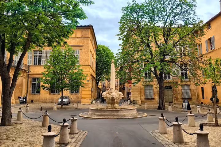 Ornate stone fountain in a charming square surrounded by golden buildings and trees in Aix-en-Provence, France