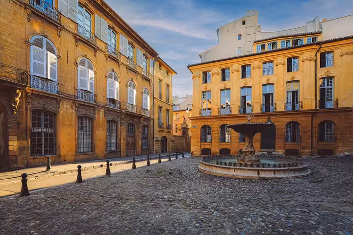 Charming cobblestone square in Aix-en-Provence surrounded by historic yellow buildings, perfect for a guided walk.