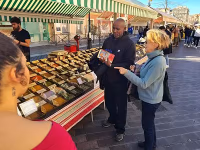 Vendor showing spices to tourists at an outdoor market stall in Aix-en-Provence