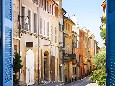 Colorful historic buildings lining a narrow sunny street in Aix-en-Provence old town
