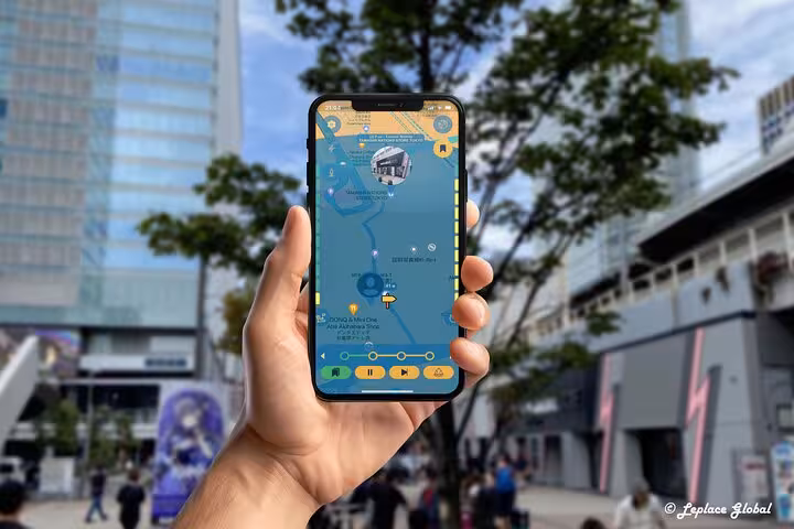 Hand holding smartphone displaying Akihabara walking tour mobile app map with anime buildings in background Tokyo
