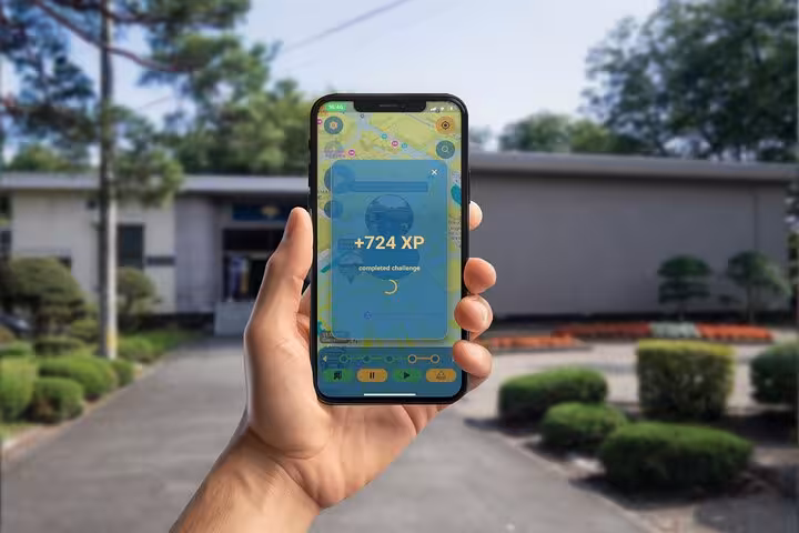 Hand holding smartphone displaying +724 XP reward on GPS walking tour app in Akita City