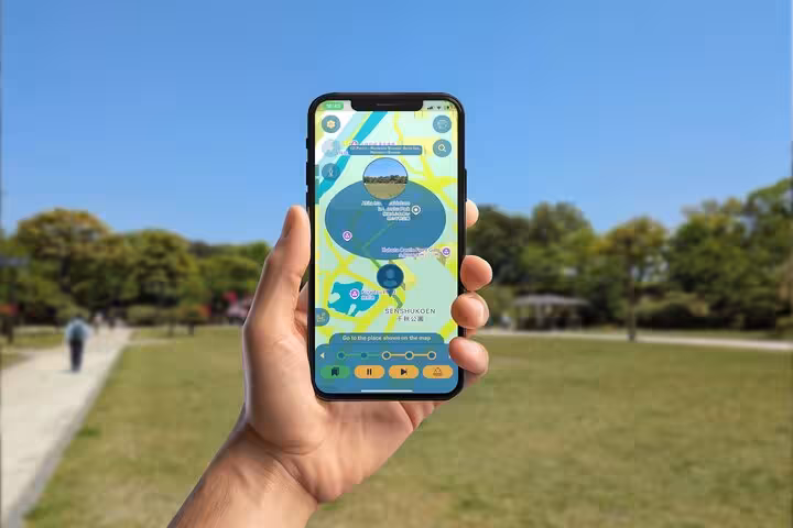 Hand holding smartphone displaying GPS walking tour map app at Senshukoen park in Akita City