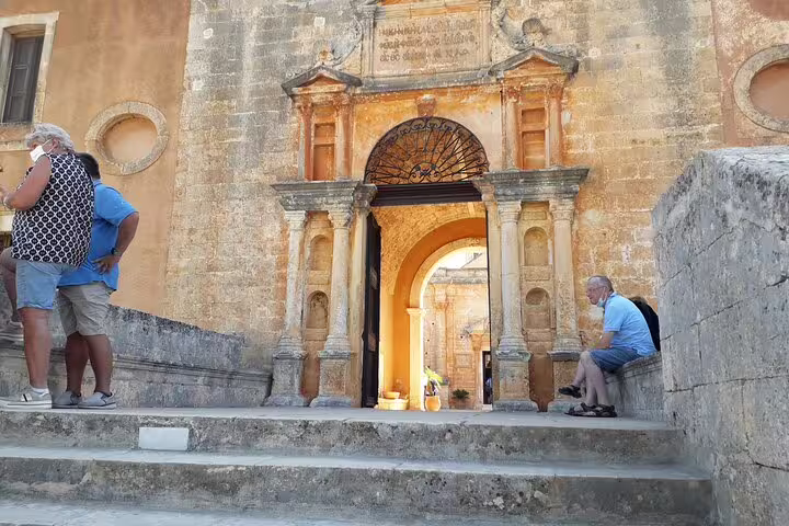 Visitors exploring the ancient architecture of a historic monastery entrance on the Akrotiri Peninsula hiking tour.