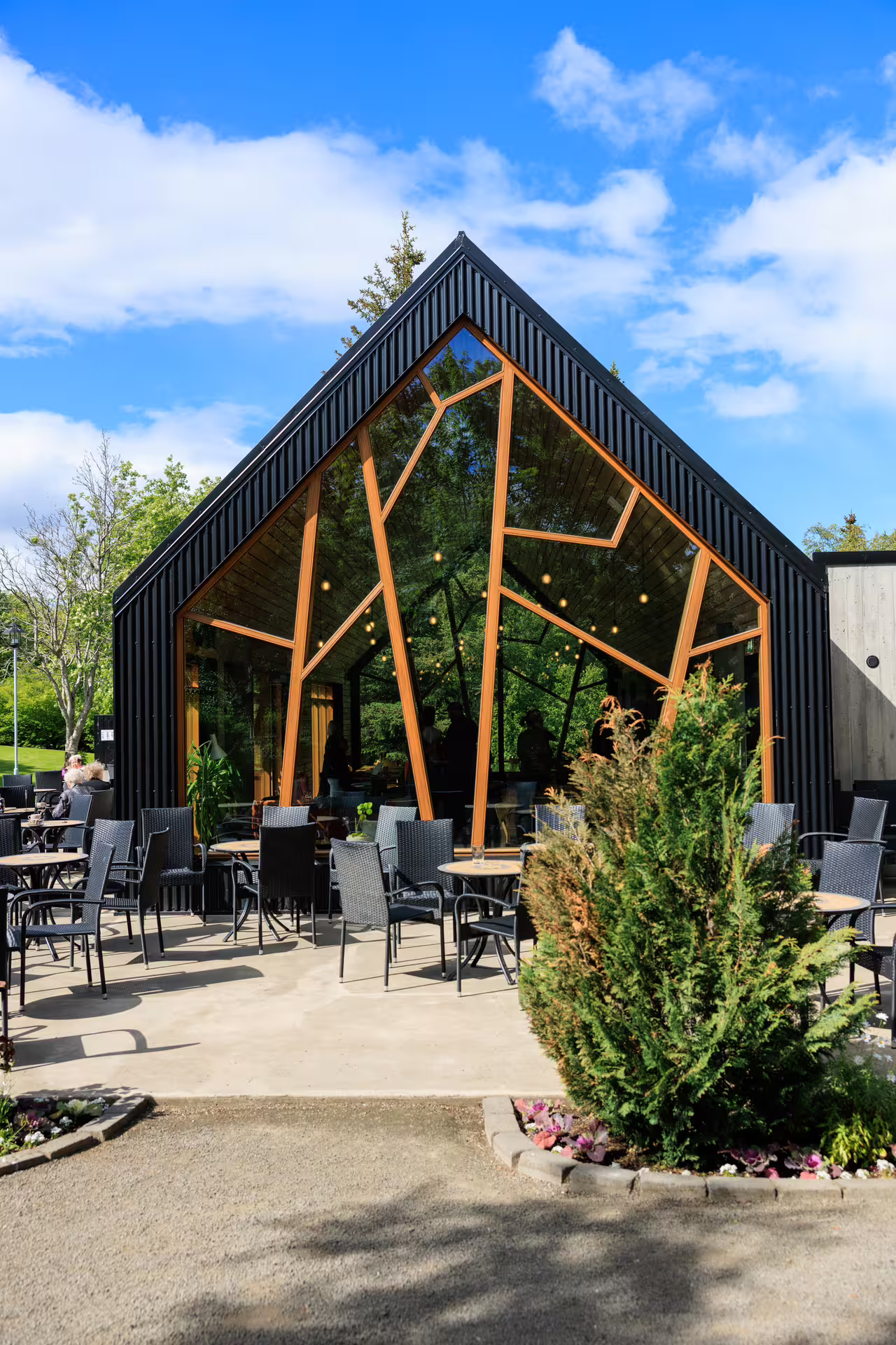 Modern glass and timber café building with outdoor seating at Akureyri Botanical Gardens, Iceland