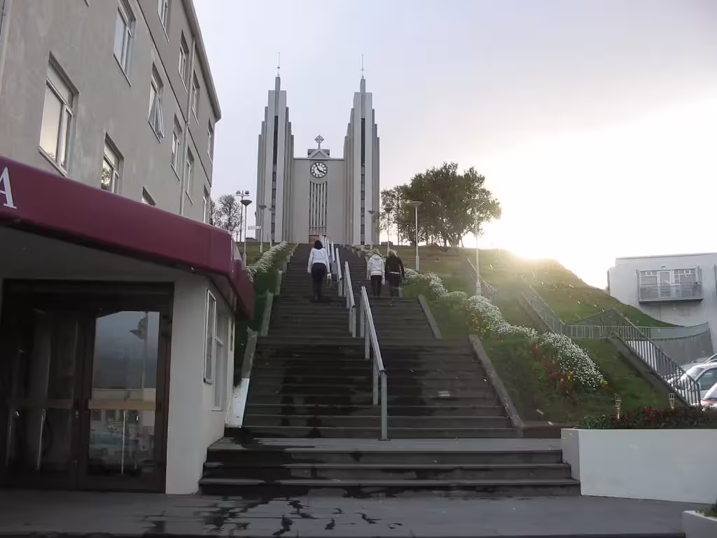 Stairs leading up to Akureyri Church with visitors climbing toward the modern concrete towers at sunset