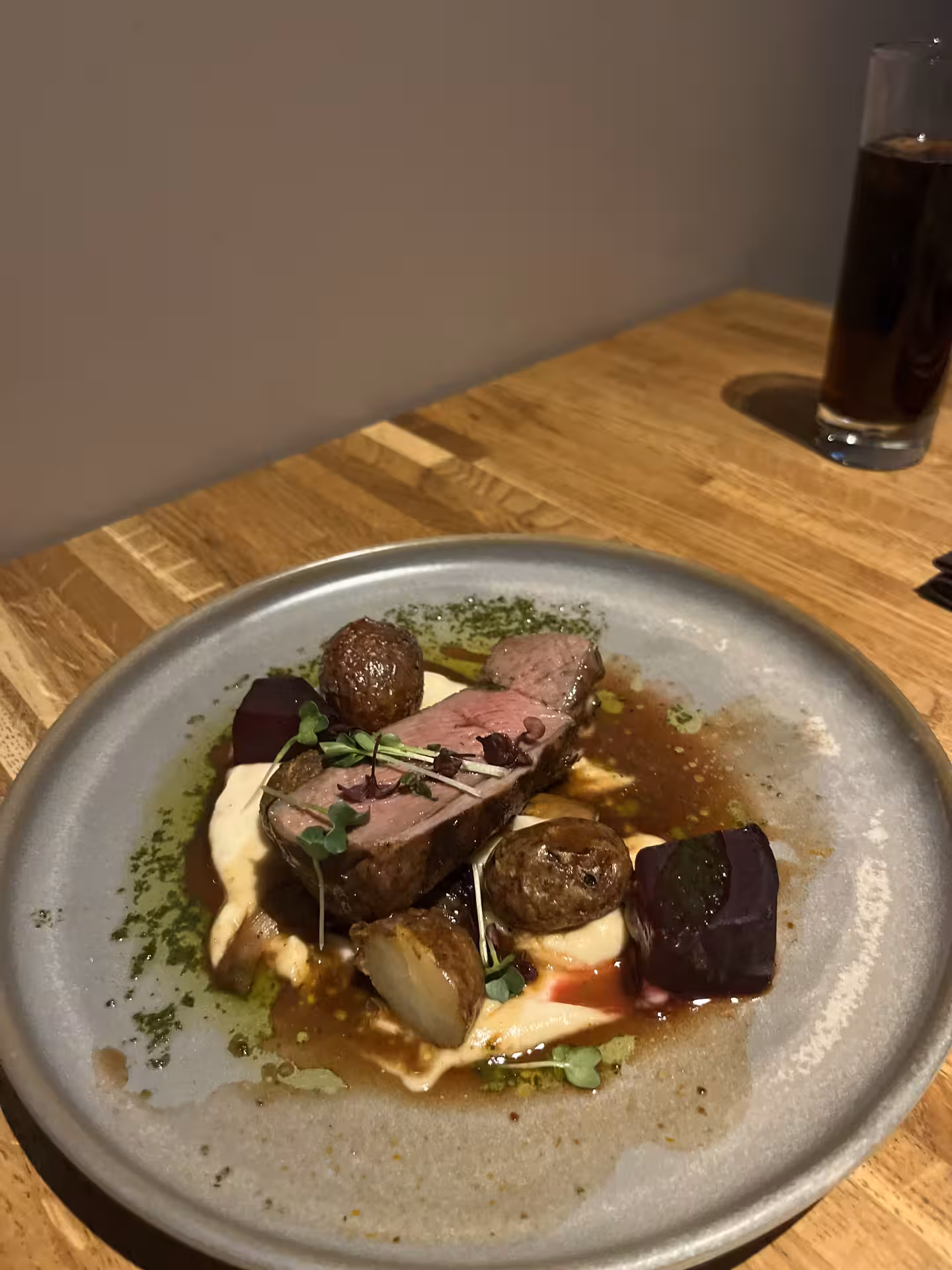 Plated lamb dish with roasted mushrooms, beetroot, and herb oil on a rustic ceramic plate in Akureyri