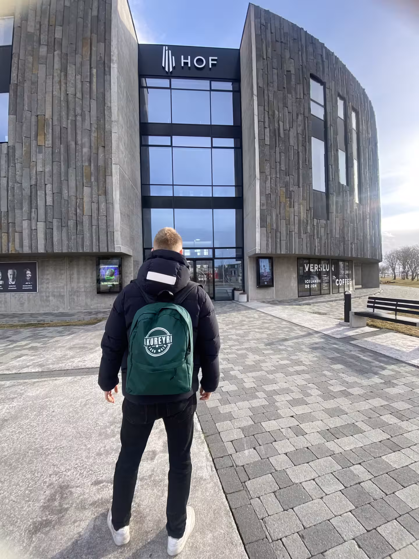 Tourist with Akureyri backpack standing in front of HOF cultural center in Akureyri, Iceland