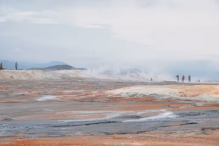 Steaming geothermal landscape near Akureyri with tourists exploring colorful mineral-rich terrain