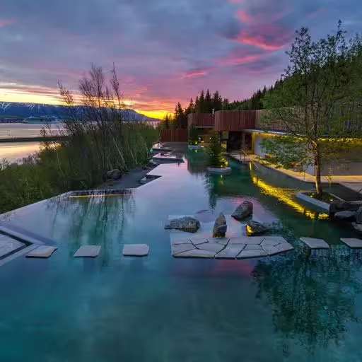 Geothermal infinity pool at sunset near Akureyri with mountain lake views and natural rock features