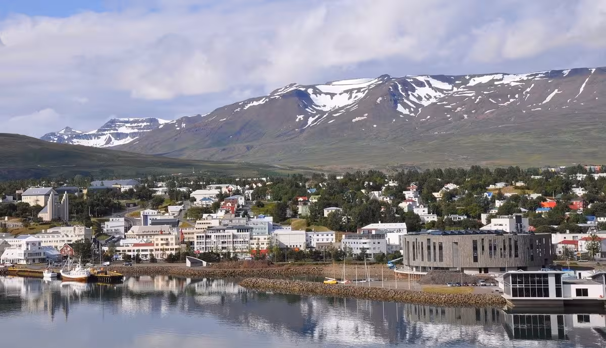 Akureyri harbor and town with snow-capped mountains reflected in calm fjord waters, Iceland