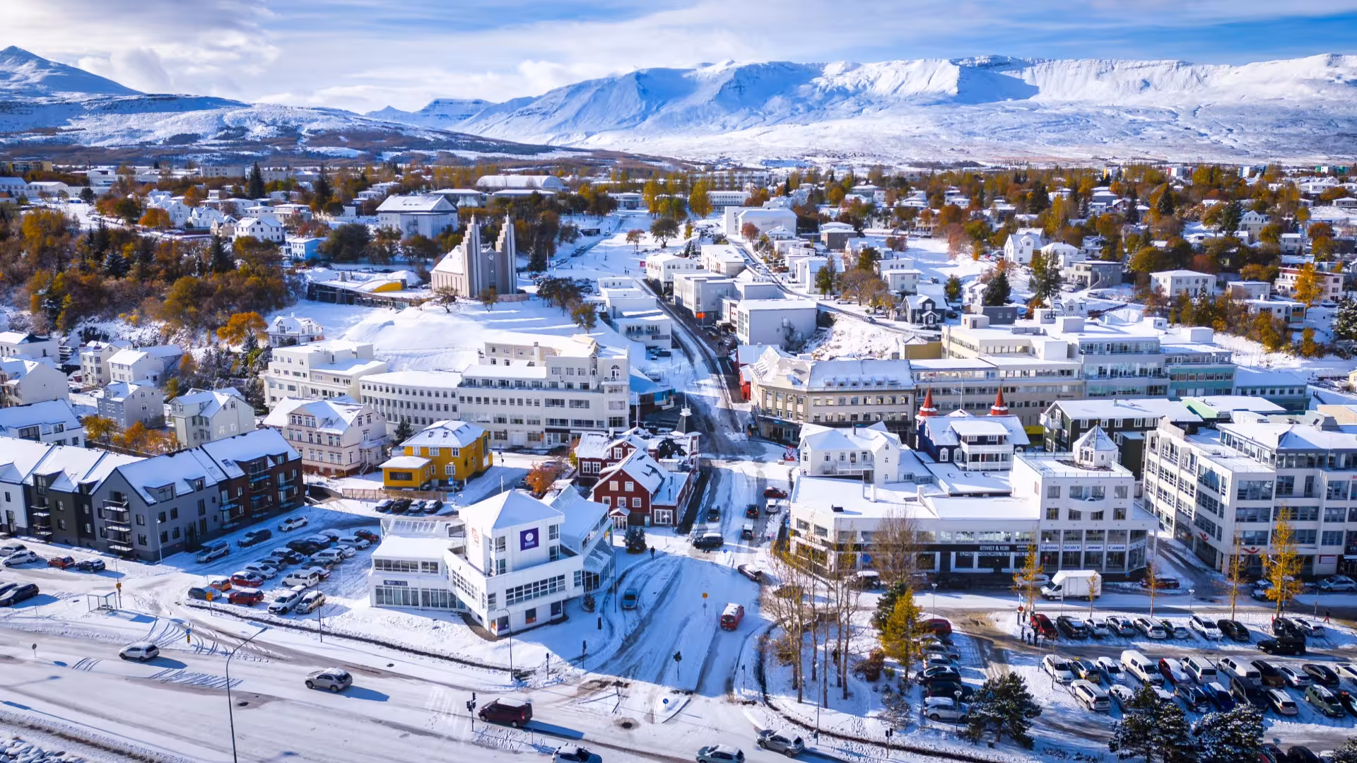 Aerial winter view of Akureyri city center with snow-covered rooftops and mountains in background