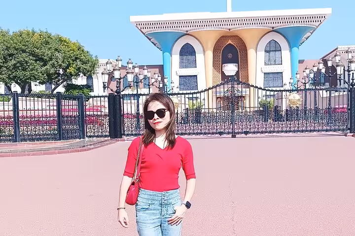 Tourist posing in front of Al Alam Palace ornate gates on a private Muscat city tour in Oman