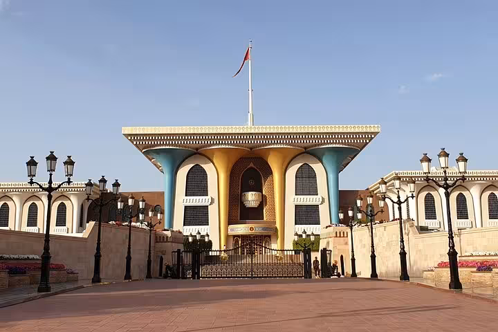 Al Alam Palace golden facade with Omani flag at dusk during Muscat evening heritage walking tour