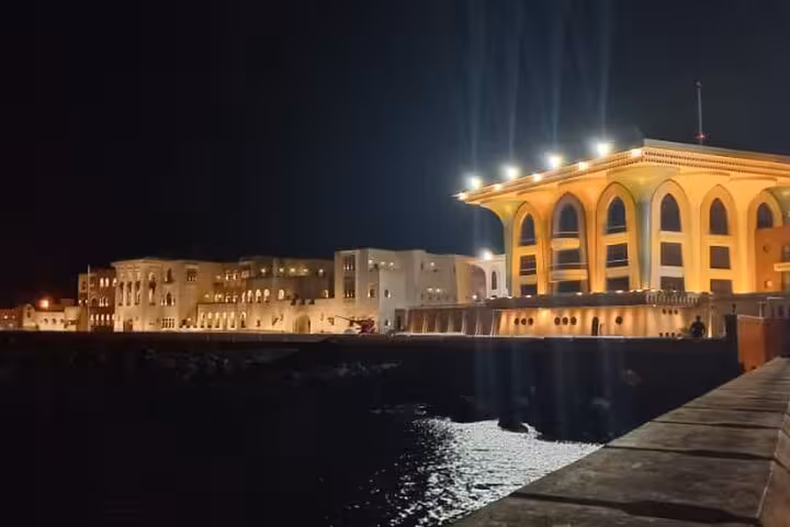 Al Alam Palace glowing with golden lights at night during Muscat evening walking tour of the old quarter