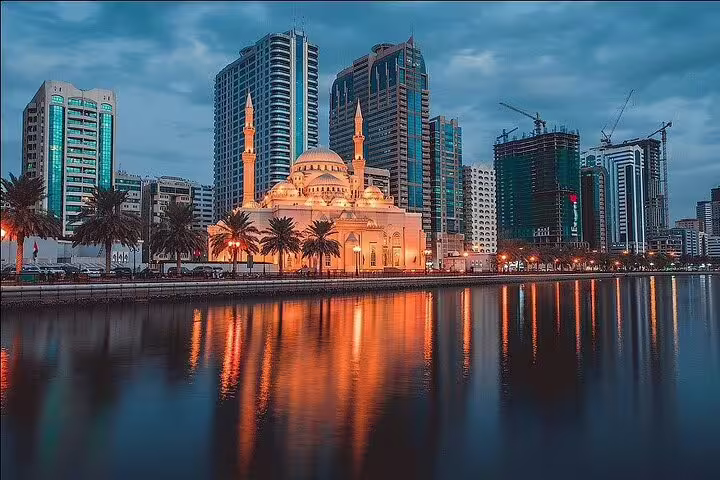 Scenic view of Al Noor Mosque illuminated at dusk along Sharjah's waterfront on the Six Emirates Tour from Dubai.