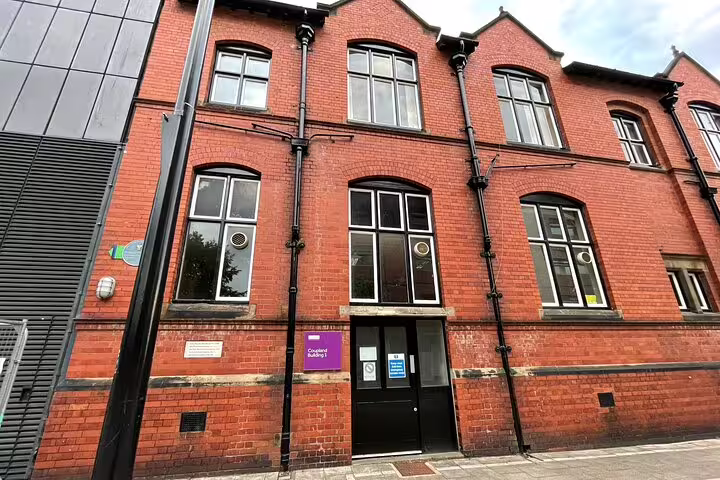 Historic red brick Victorian building in Manchester with arched windows and black drainpipes