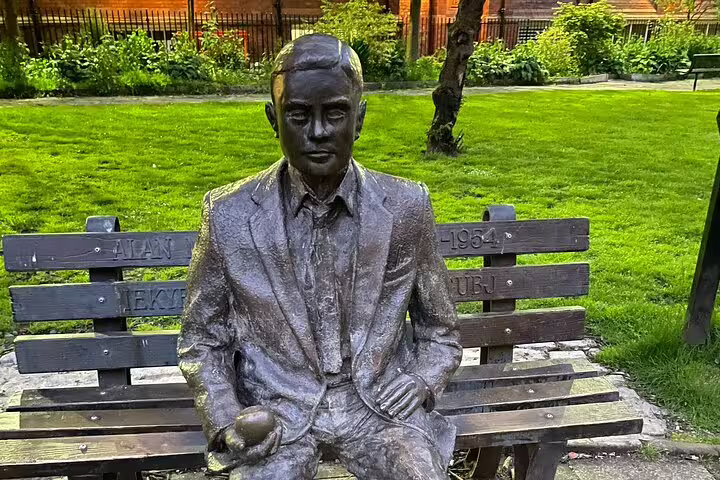Bronze statue of Alan Turing seated on a bench in Sackville Gardens, Manchester, holding an apple