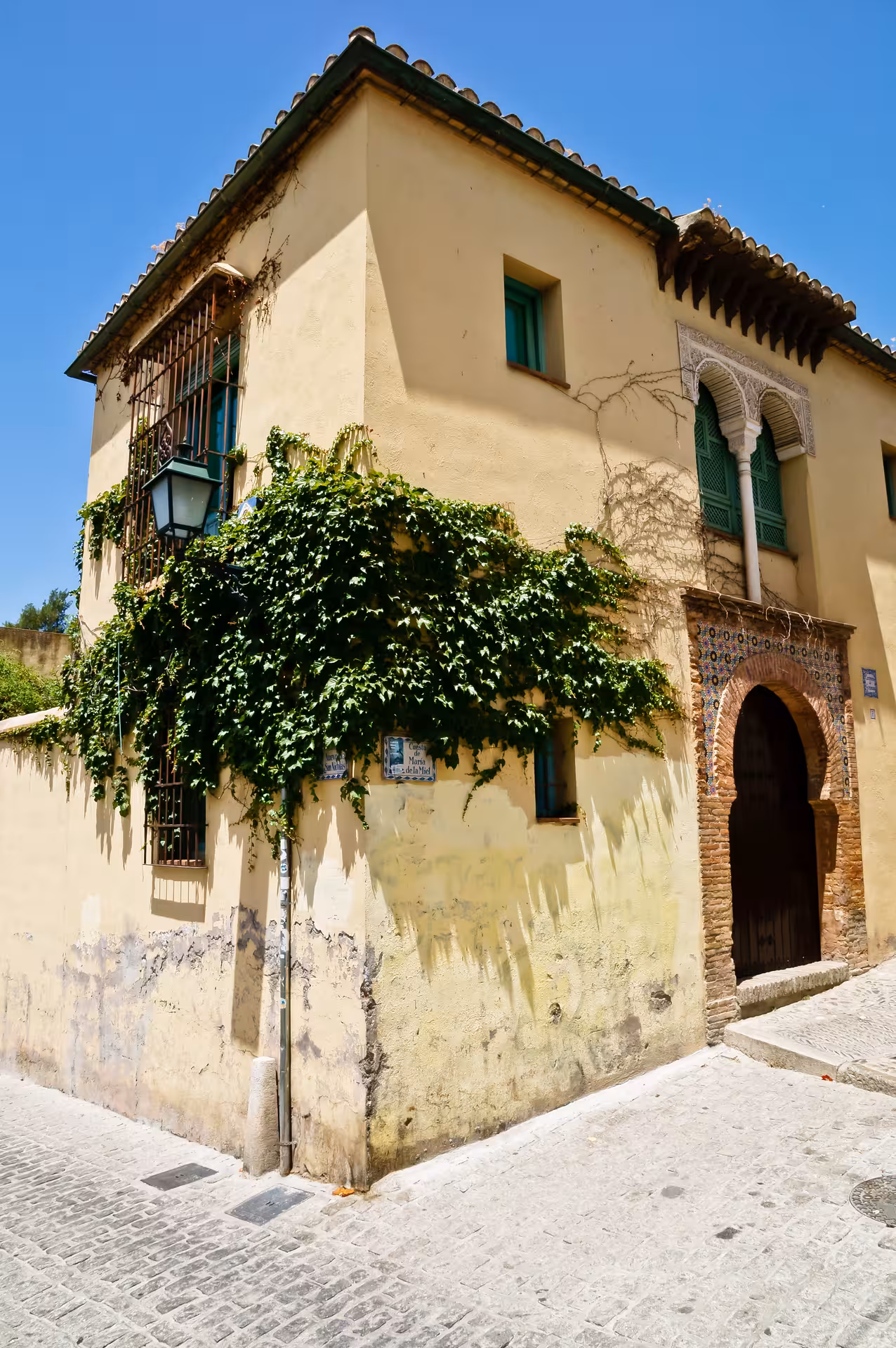 Charming ivy-covered house in the Albaicín, showcasing traditional Moorish architecture under a clear blue sky.