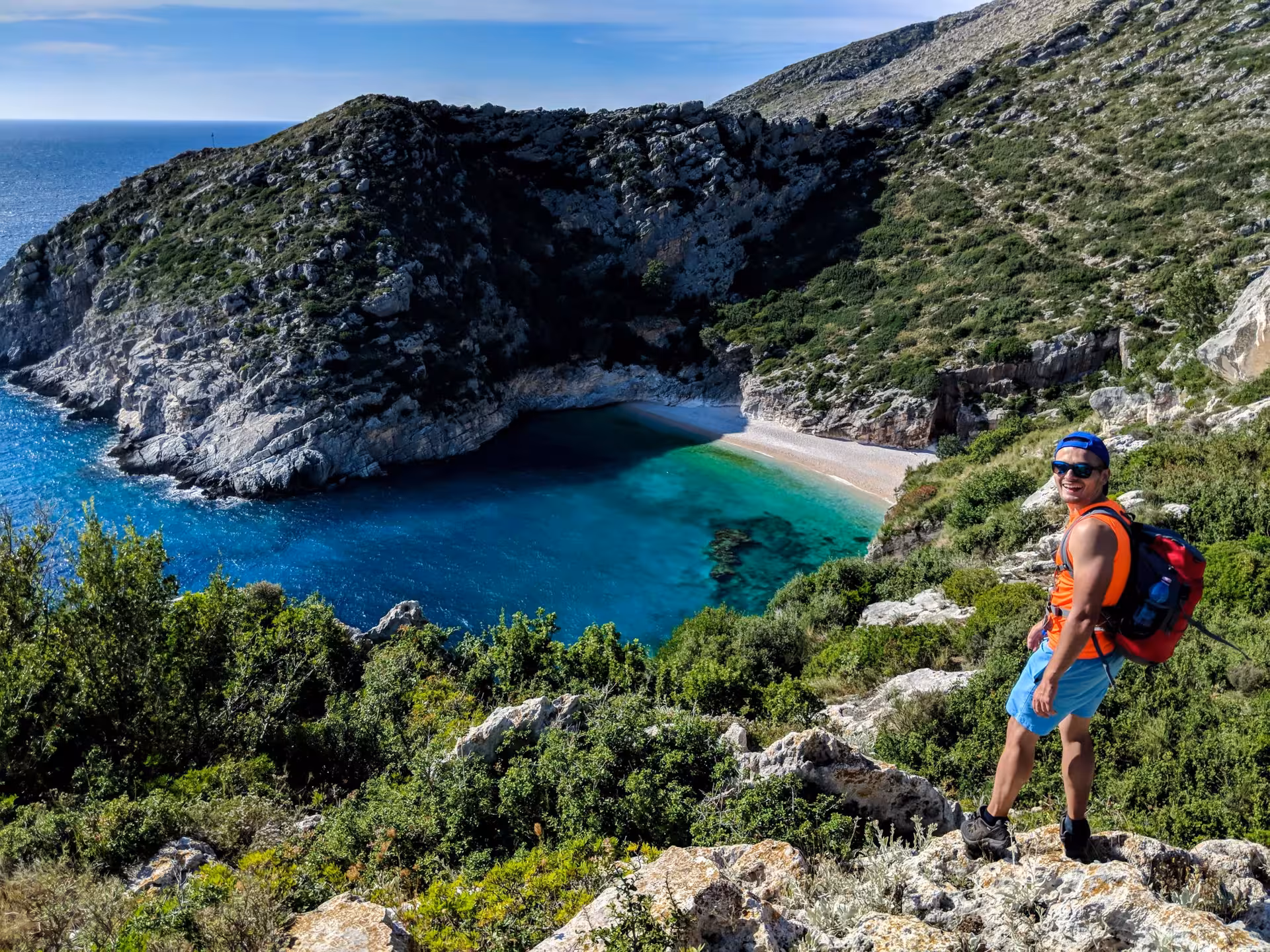 Hiker overlooking a secluded cove with turquoise waters on the Albanian Riviera, perfect for adventure seekers.