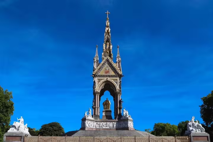 Albert Memorial Gothic spire with golden statue in Kensington Gardens London under blue sky