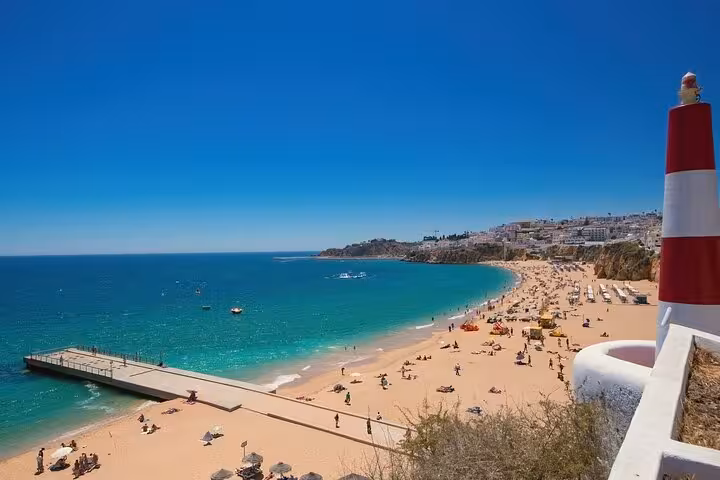 Scenic view of Albufeira's sunlit beach with a vibrant blue ocean, perfect for a guided city walk exploration.