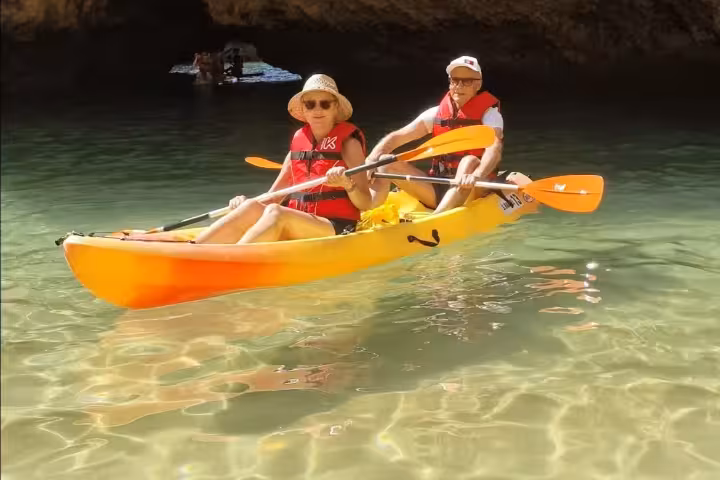 Couple kayaking in crystal clear turquoise waters near Albufeira caves on a guided sea kayak tour Algarve