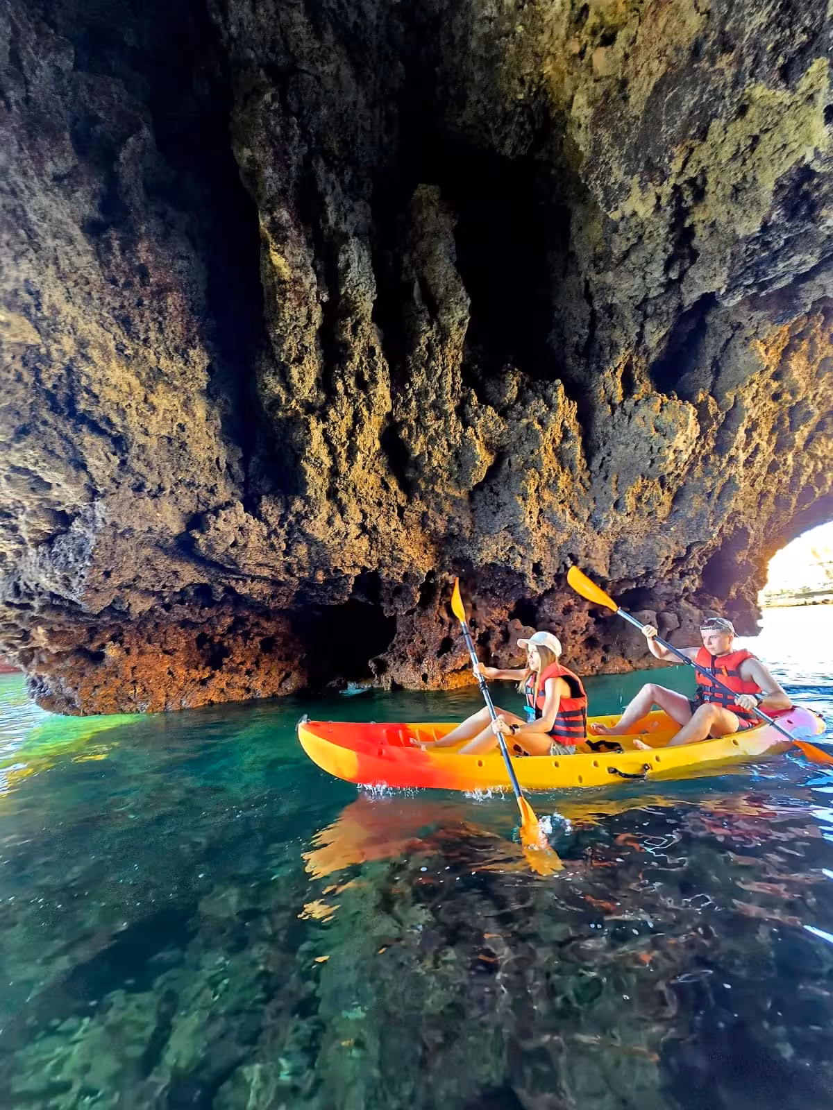 Two kayakers exploring a dramatic sea cave on a private Albufeira kayak tour in crystal-clear waters