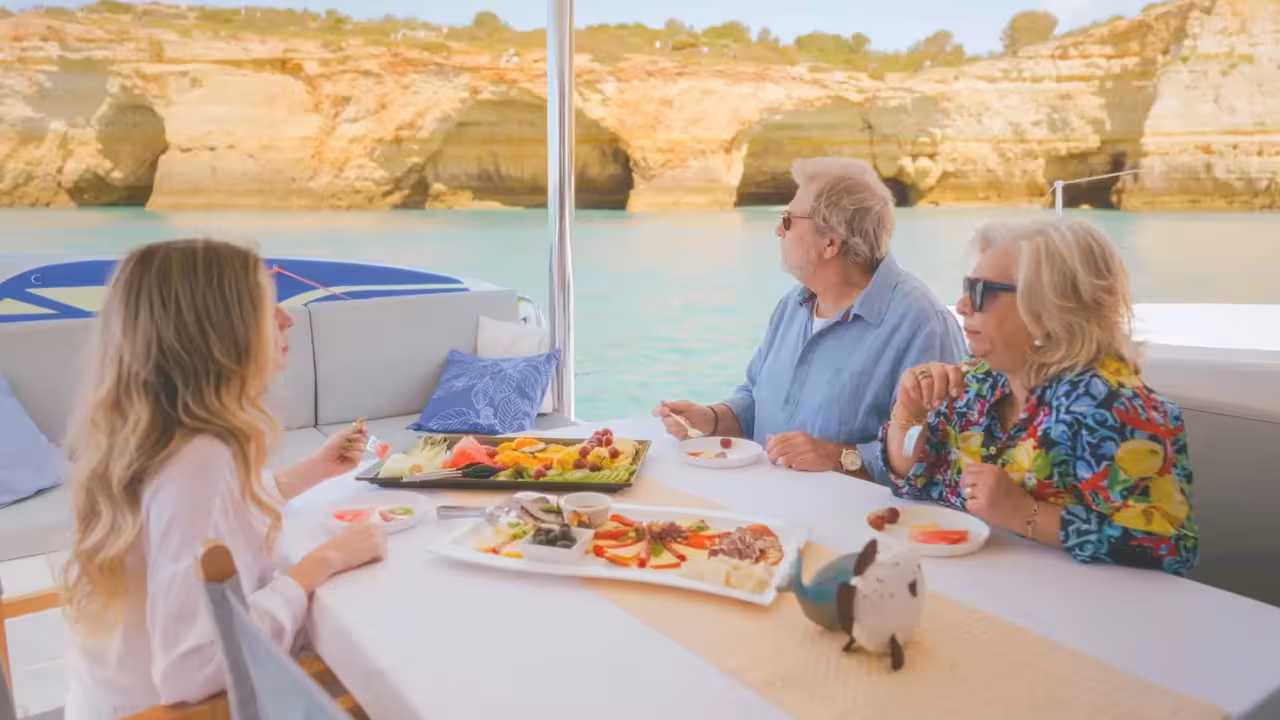 Guests enjoying gourmet dining on an Albufeira sunset cruise with scenic Algarve cliffs in the background