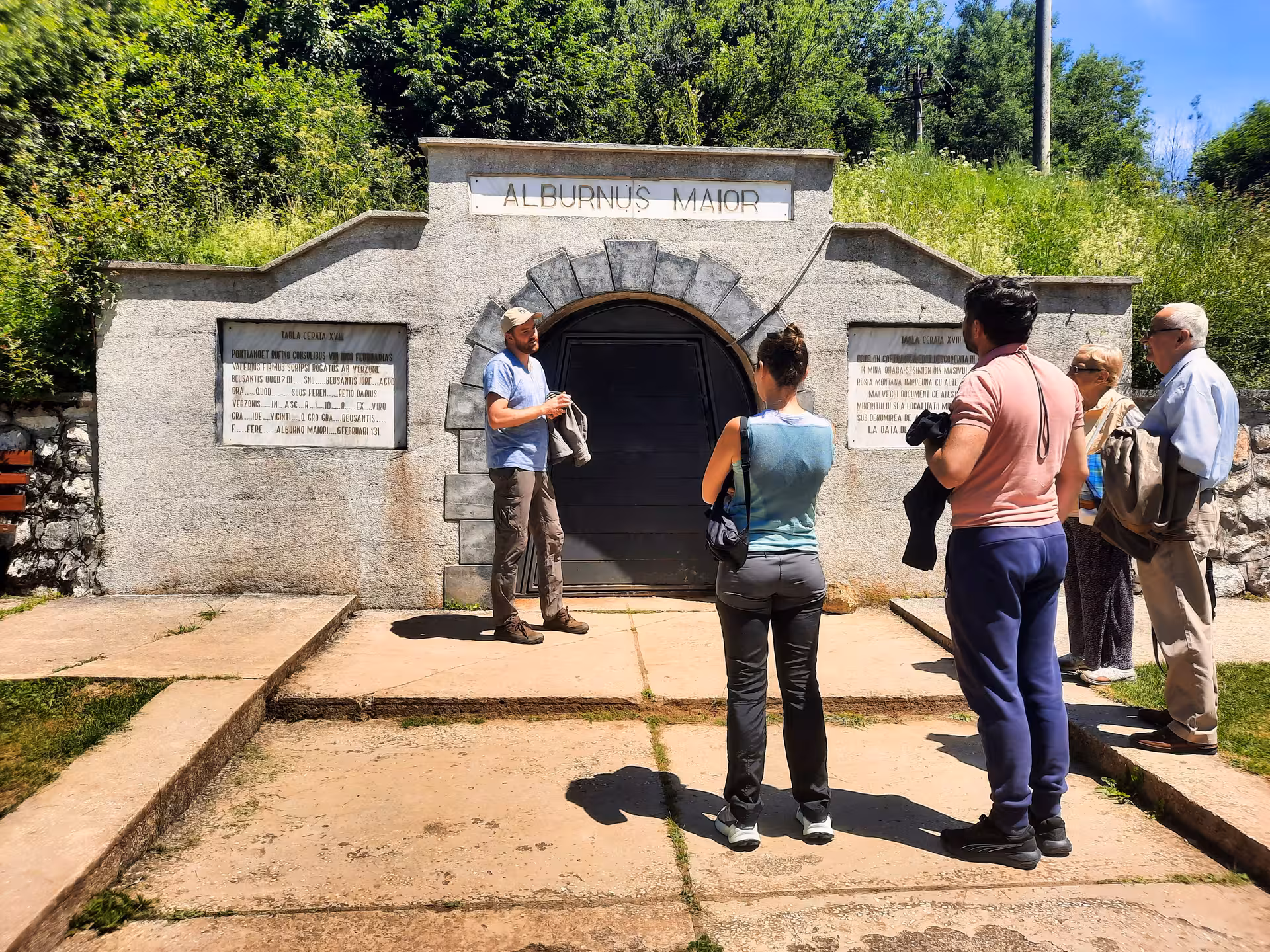 Tour guide explaining history at Alburnus Maior Roman mine entrance in Rosia Montana, Apuseni Mountains