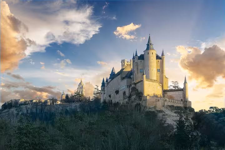 Stunning view of Alcazar of Segovia illuminated by sunset, showcasing its fairy-tale architecture and towers.