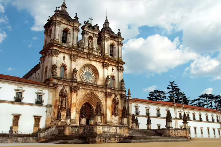 Historic Alcobaça Monastery in Portugal, showcasing Gothic architecture under a bright blue sky, perfect for cultural tours.