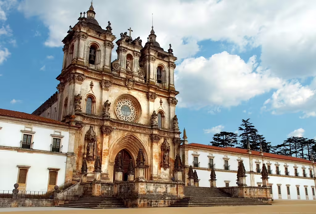 Historic Monastery of Alcobaça with stunning architecture under a clear blue sky, featured in Portugal North and South self-drive tour.