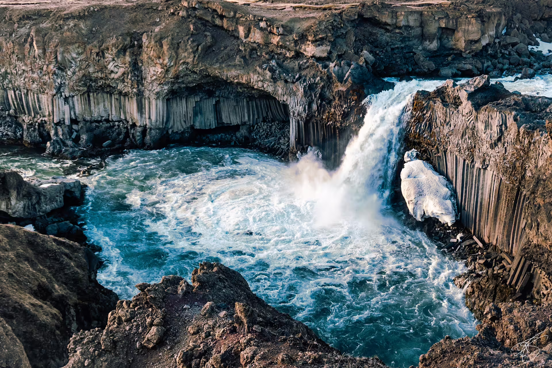 Aldeyjarfoss waterfall cascading into turquoise pool surrounded by basalt columns in North Iceland