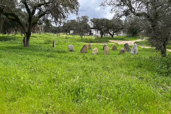 Serene Alentejo landscape with ancient standing stones surrounded by lush greenery and oak trees.