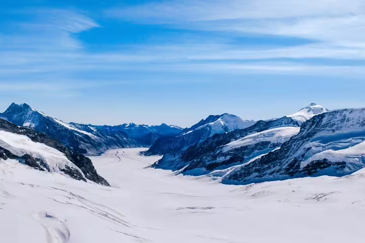Expansive view of the Aletsch Glacier surrounded by snow-capped peaks under a clear blue sky at Jungfraujoch.