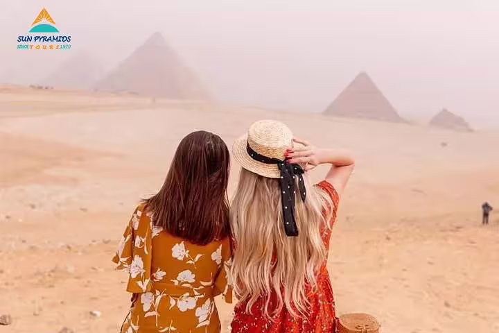 Two women viewing the Pyramids of Giza in the desert, part of an Alexandria to Abu Simbel wheelchair-friendly itinerary