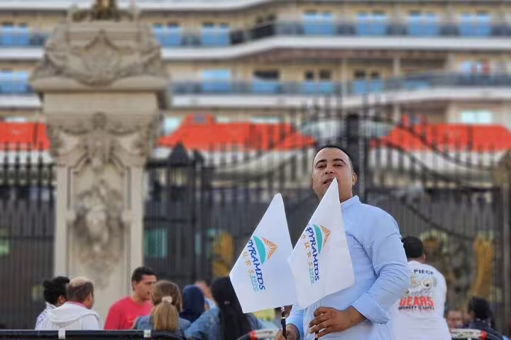 Tour guide holding flags at pickup for Alexandria Port to Pyramids and Grand Egyptian Museum day tour