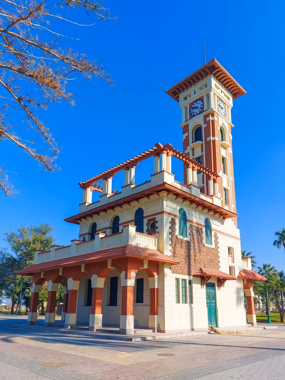 Historic clock tower building with red and cream facade in Alexandria Royal Gardens on a sunny day