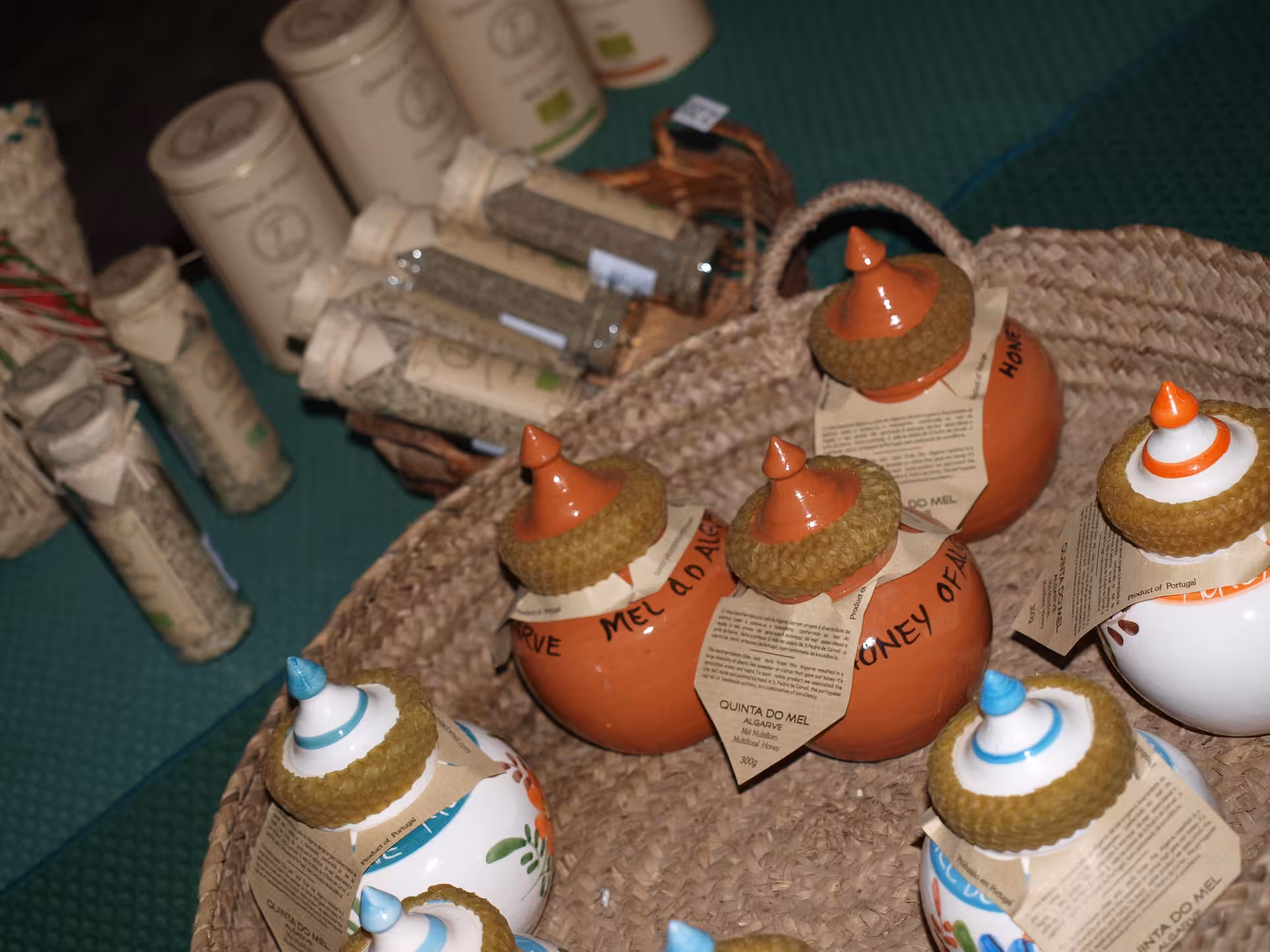 Close-up of Algarve artisanal honey jars and dried herb tubes arranged in a woven basket at a traditional farm shop