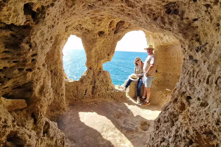 Couple enjoying stunning ocean views through natural rock formations on Algarve private tour with Benagil Caves boat trip.