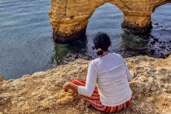 Traveler overlooking Algarve sea arch near Benagil on private Lisbon to Algarve tour with boat caves trip