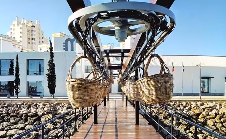 Guided Algarve Cans & Bottles tour showing conveyor baskets at a modern waterfront cannery in Portimão, Portugal