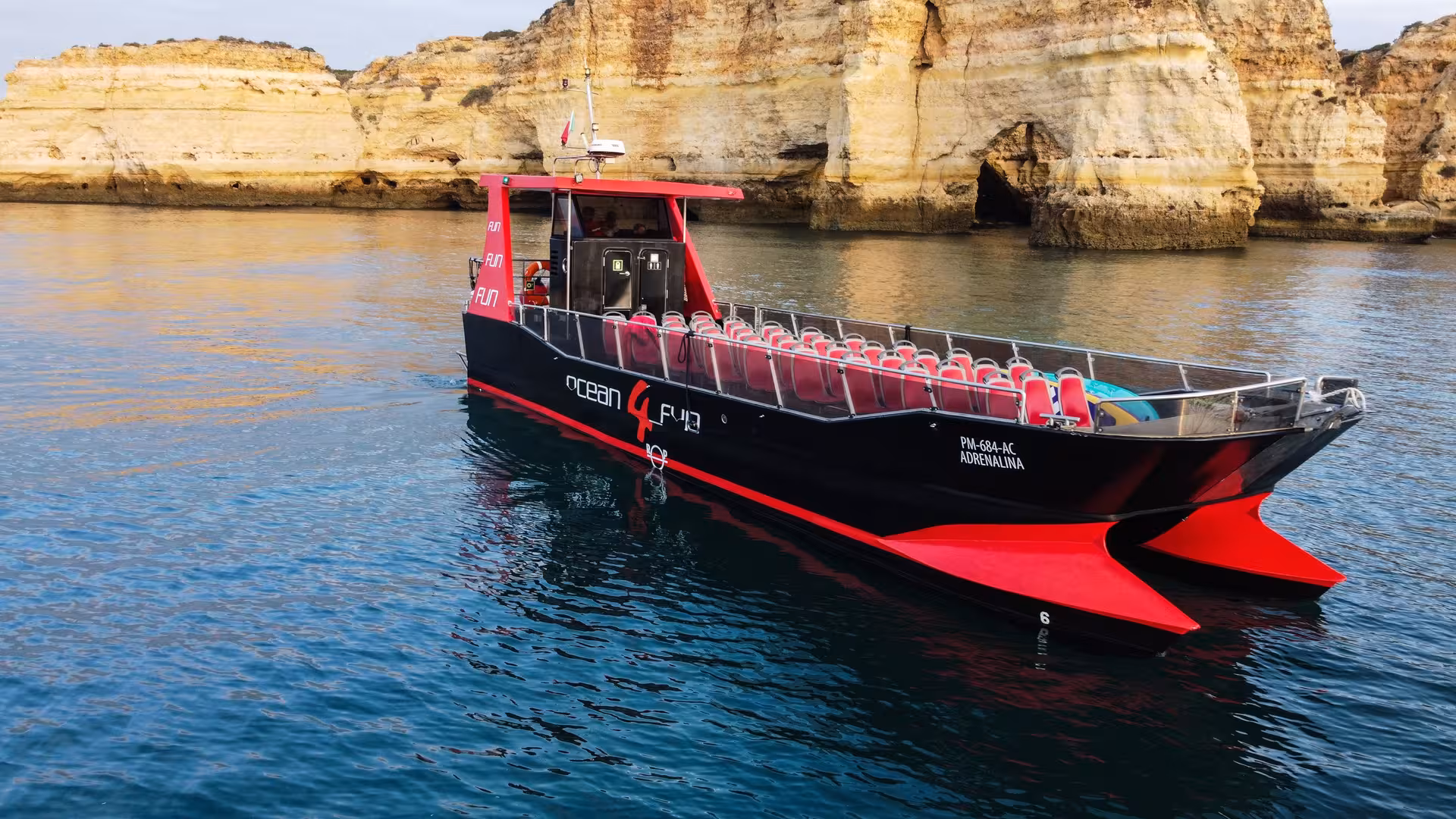 Ocean 4 Fun Adrenalina catamaran cruising past stunning golden limestone cliffs on Algarve coast tour