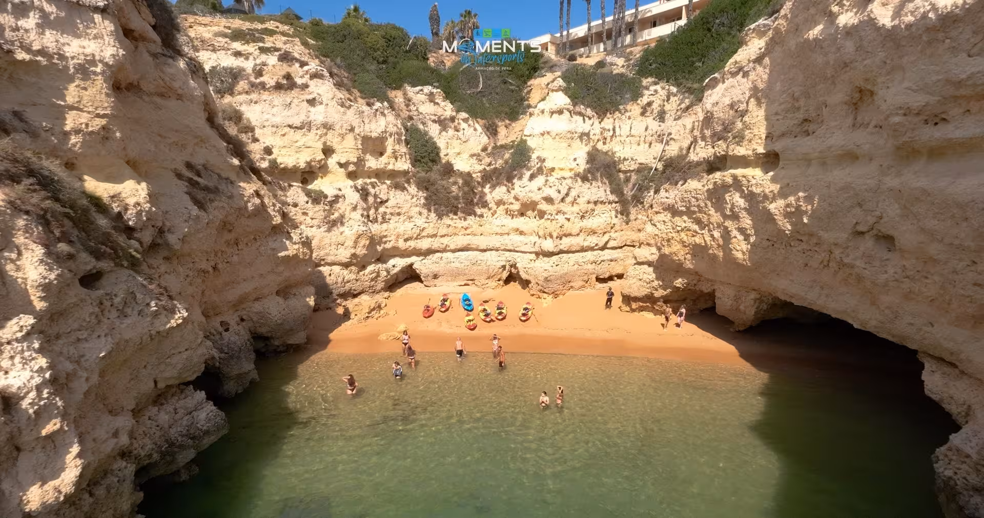 Aerial view of kayakers resting on a secluded Algarve wild beach surrounded by golden limestone cliffs