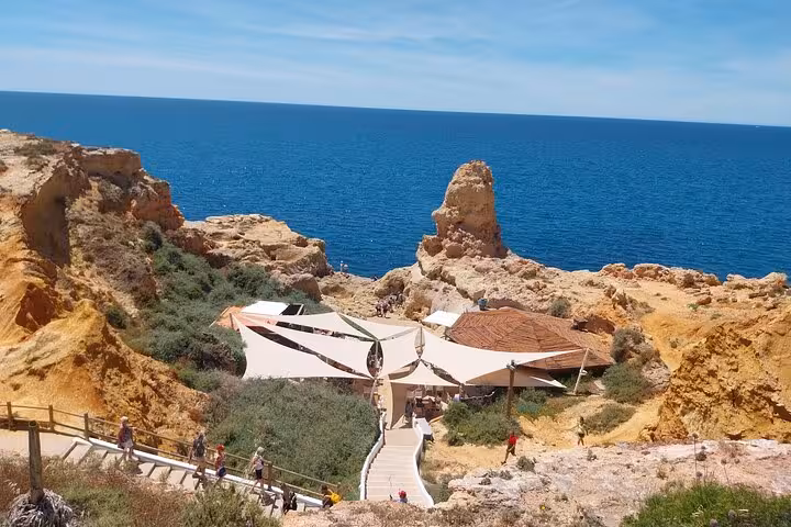 Scenic coastal walkway leading to a charming beach cafe surrounded by rocky cliffs and ocean views in Algarve.