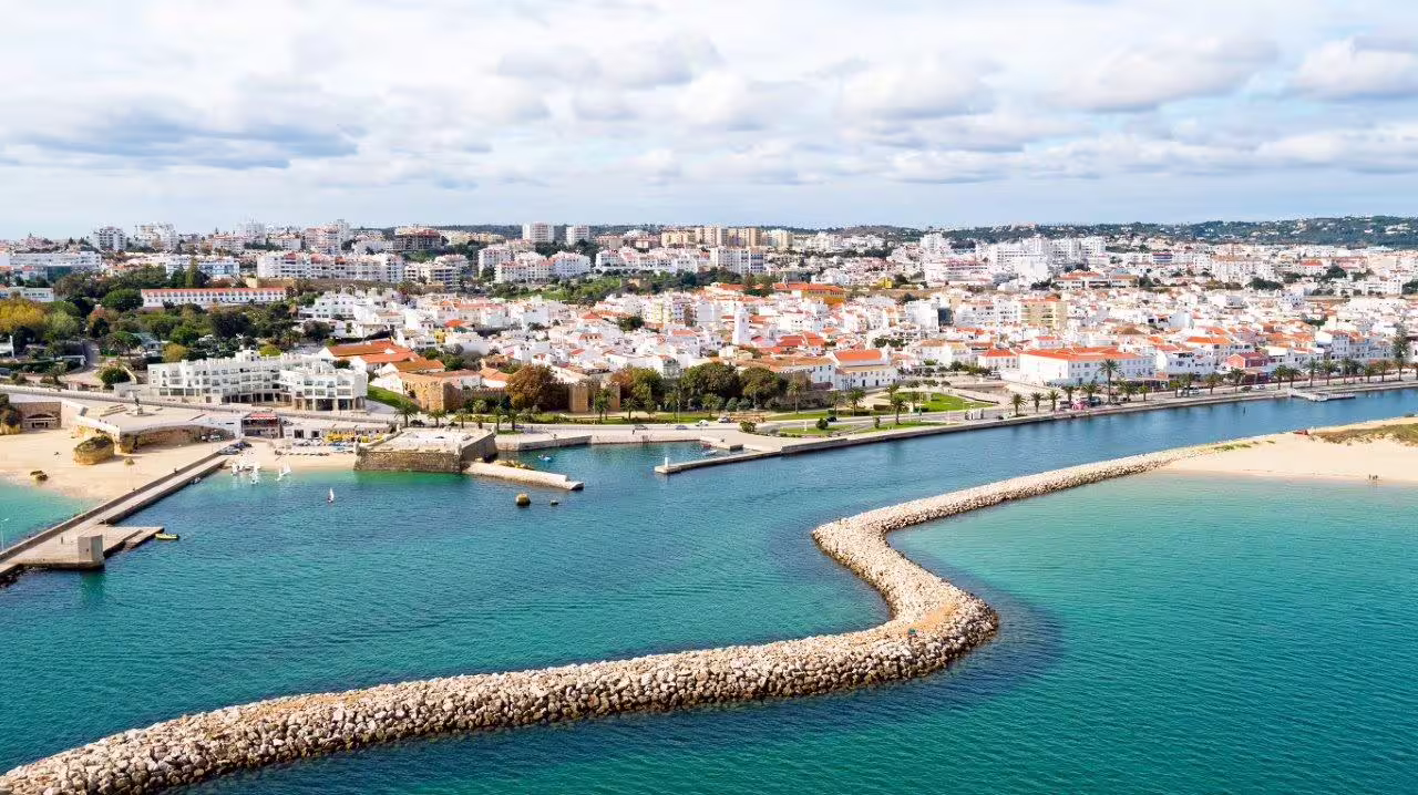 Aerial view of Algarve's stunning coastline and charming town, perfect for exploring on a self-drive tour through Portugal.