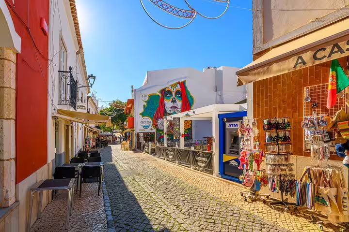 Colorful cobblestone street in Algarve town, local shops and murals on Faro to Sagres private coastal journey